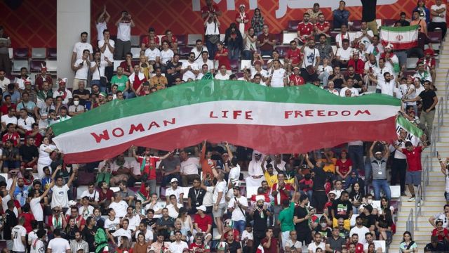 Penggemar Iran mengangkat spanduk bertuliskan 'Perempuan, Hidup, Kebebasan' selama pertandingan Grup B Piala Dunia FIFA Qatar 2022 antara Inggris dan Iran di Stadion Internasional Khalifa pada 21 November 2022 di Doha, Qatar