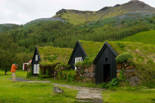 Turis memotret rumah rumput tradisional di Museum Cerita Rakyat Skogar di Islandia selatan.